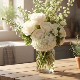 White roses and hydrangeas arranged in a clear glass vase