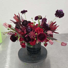 Deep red and burgundy bouquet in a black vase