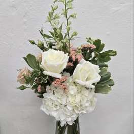 White roses and hydrangea in a clear glass vase with pink accents