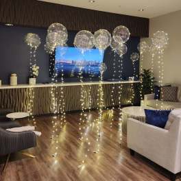 Living room decorated with clear balloons and string lights