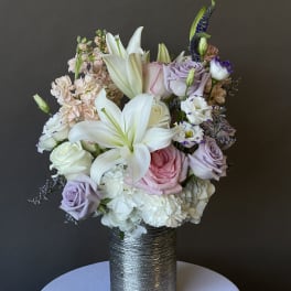 Pastel bouquet of lilies, roses, and carnations in a silver vase