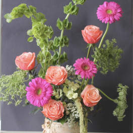 Pink roses and gerbera daisies in a birch bark container