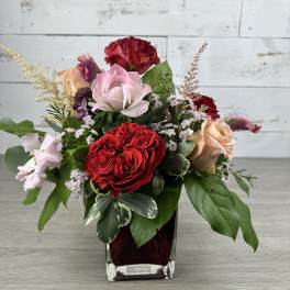 Mixed rose arrangement in a square glass vase