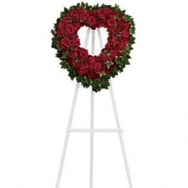 Heart-shaped red rose wreath on a white easel stand