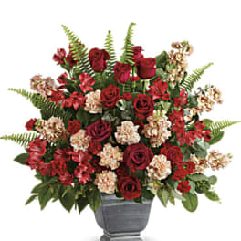 Red roses and carnations arranged in a gray urn vase