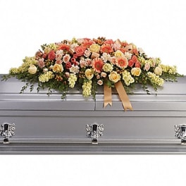 Casket spray of peach, pink, and cream flowers