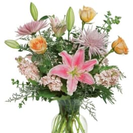 Pink lilies and roses arranged in a clear glass vase