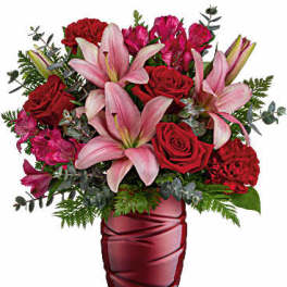 Bouquet of pink lilies and red roses in a red glass vase