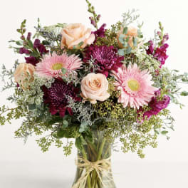 Mixed bouquet of pink and peach flowers in a clear glass vase