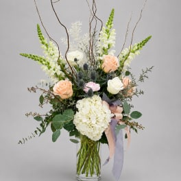 Tall bouquet of white and peach flowers in a clear glass vase