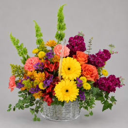 Colorful mixed flower arrangement in a clear basket vase