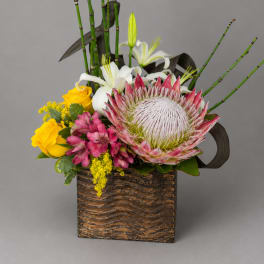 Mixed floral arrangement in a textured square container with pink and white blooms