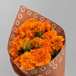 Bouquet of orange marigolds wrapped in patterned brown paper with a burlap bow