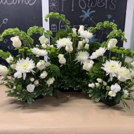 White roses and chrysanthemums arranged with green accents in a low centerpiece