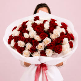 Large bouquet of red and white roses wrapped in white paper with a red ribbon