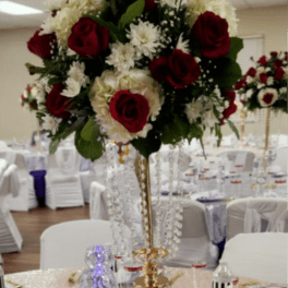 Tall centerpiece with red roses and white flowers in a gold stand
