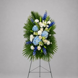 Standing floral wreath with blue and white flowers on an easel