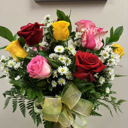 Bouquet of multicolored roses and white daisies in a glass vase