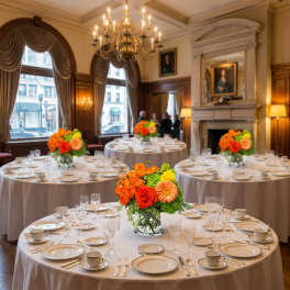 Round banquet tables with orange and yellow floral centerpieces in a formal room