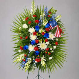 Standing floral wreath with red, white, and blue flowers and an American flag