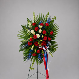 Standing floral wreath with red, white, and blue flowers on an easel