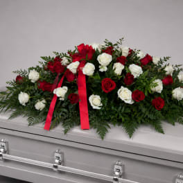 Red and white rose spray on a silver casket