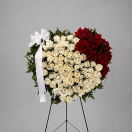 Heart-shaped standing arrangement of red and white roses on an easel with a white ribbon