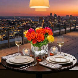 Rose centerpiece in a square glass vase on a candlelit dinner table