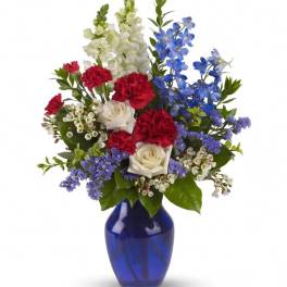 Mixed bouquet of red, white, and blue flowers in a blue vase