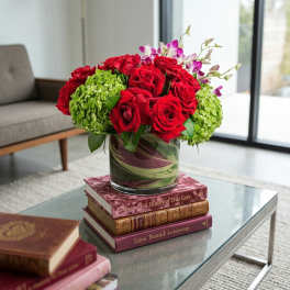 Red roses and green hydrangeas in a glass vase on stacked books