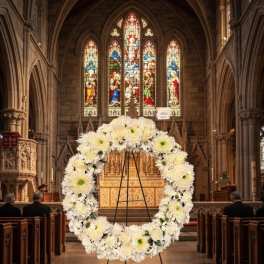 White floral wreath on a stand inside a church