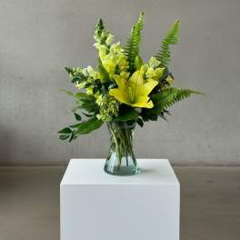 Yellow lilies and snapdragons in a clear glass vase