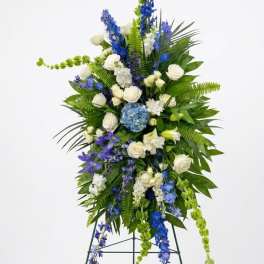 Tall standing floral spray with white and blue flowers on a metal easel