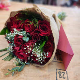 Bouquet of red roses wrapped in burlap with pink paper