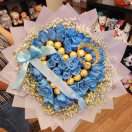 Blue rose bouquet with baby’s breath, gold chocolates, and a blue ribbon