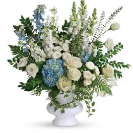 White and blue floral arrangement in a white pedestal vase