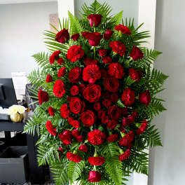 Standing spray of red roses and carnations with fern greenery