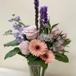 Mixed bouquet of pink and purple flowers in a clear glass vase