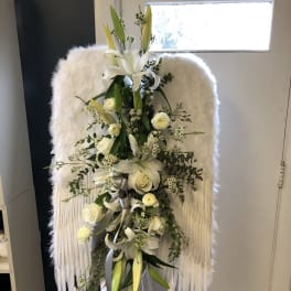 White floral standing spray on an easel with lilies and roses
