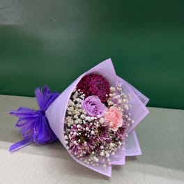 Bouquet of purple, pink, and white flowers wrapped in lavender paper