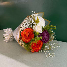 Bouquet of orange roses, white blooms, and purple flowers wrapped in paper