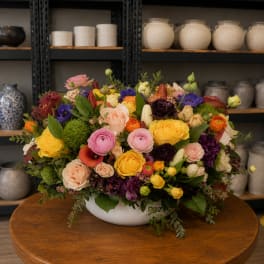 Colorful mixed flower arrangement in a white bowl vase