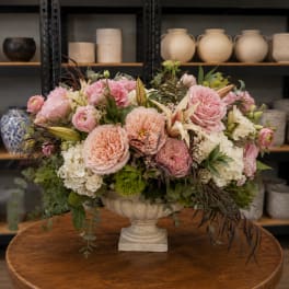 Pink and peach floral arrangement in a pedestal vase