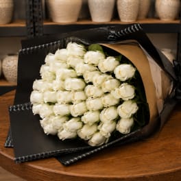 Bouquet of white roses wrapped in black paper