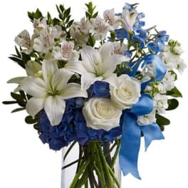 Blue and white bouquet in a clear glass vase with a ribbon