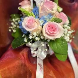 Pink roses and blue flowers in a small bouquet with a ribbon