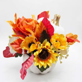 Artificial autumn floral arrangement in a white pumpkin vase
