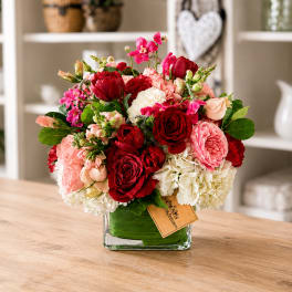 Red, pink, and white bouquet in a square glass vase
