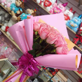 Pink rose bouquet wrapped in pink paper with a purple ribbon