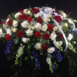Large red and white floral spray with ribbon on a dark background